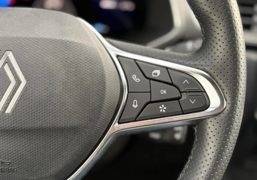 Gros plan sur le côté droit du volant perforé de la Renault SYMBIOZ 2025 avec commandes multifonctions et logo central.