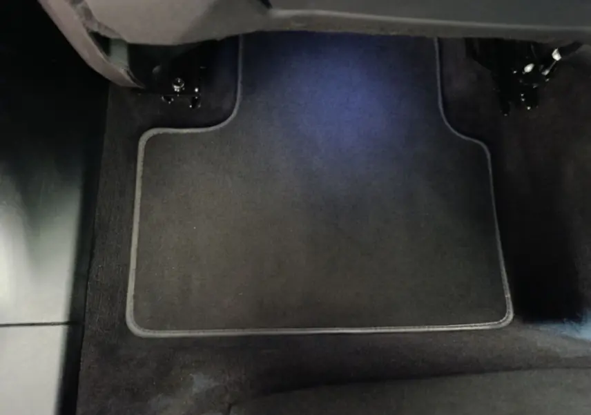 Vue rapprochée du tapis de sol noir sous le siège avant droit d'un Link & Co 01 hybride rechargeable bleu 2022.