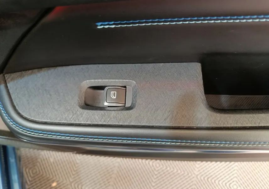 Gros plan sur la commande de lève-vitre avec surpiqûres bleues sur la garniture intérieure de porte du Link & Co 01 bleu.
