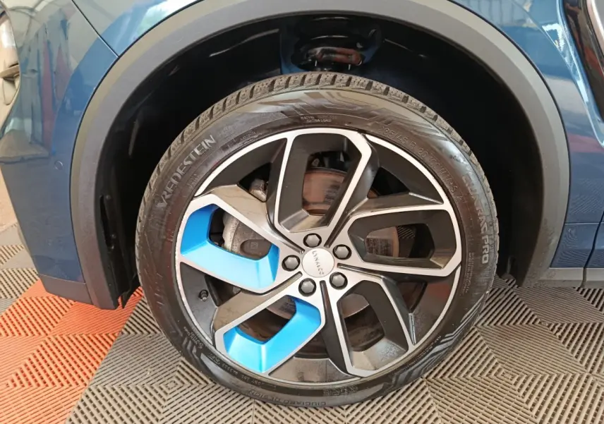 Gros plan sur la roue avant gauche d’un SUV Link & Co 01 bleu avec jante noire et accents bleus.