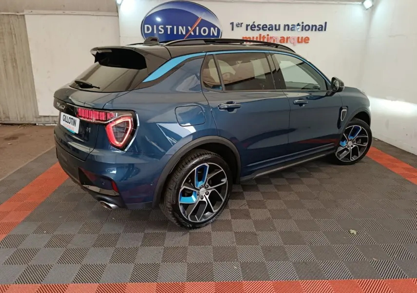 Vue 3/4 arrière droite d'un SUV Link & Co 01 bleu avec jantes bicolores et toit noir dans un garage.