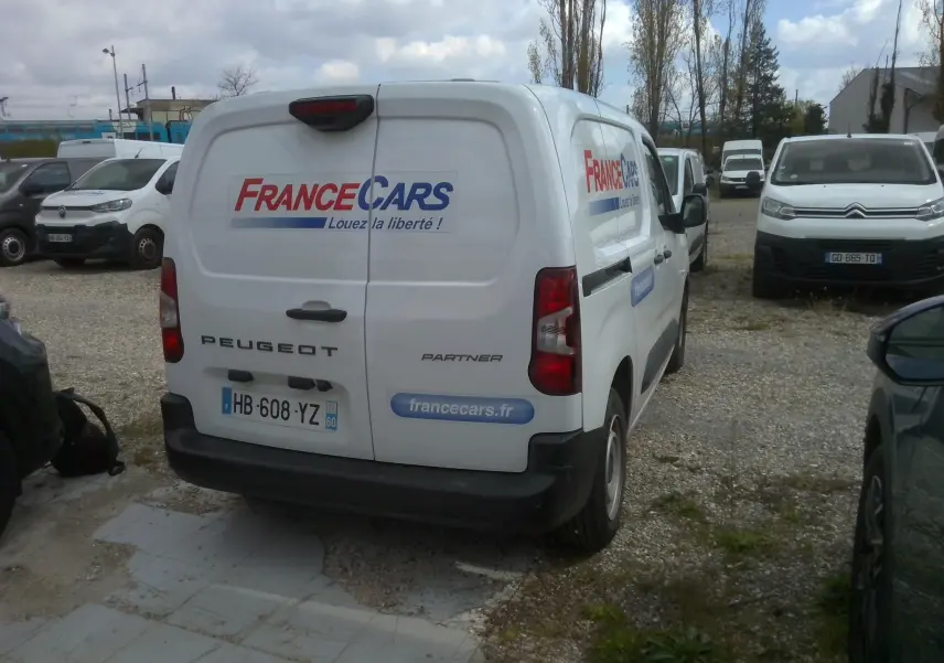 Vue 3/4 arrière droite d'un Peugeot Partner blanc avec logo France Cars et slogan "Louez la liberté" sur les portes arrière.