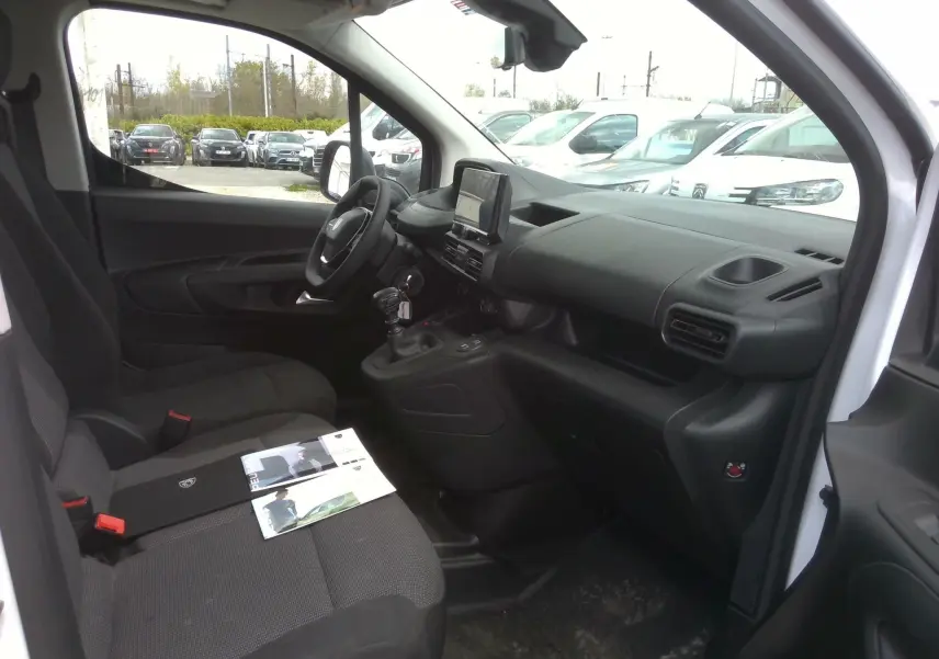 Intérieur côté conducteur du Peugeot Partner blanc 2025, montrant le tableau de bord et la console centrale avec écran GPS.
