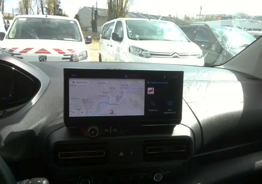 Vue intérieure du tableau de bord du Peugeot Partner blanc 2025, avec écran GPS central allumé en plein jour.