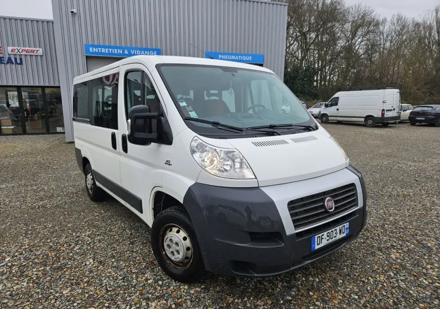 Fiat Ducato Combi blanc vu en 3/4 avant droit, avec pare-chocs noir et neuf places visibles à l'intérieur.