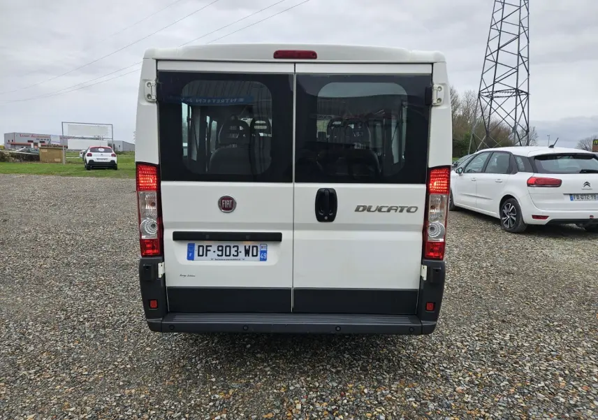 Vue arrière d'un FIAT Ducato Combi blanc 2014, version 9 places, avec portes vitrées et feux allumés.