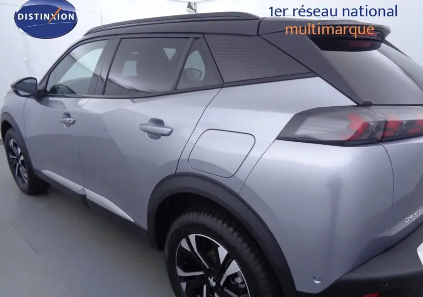 Vue 3/4 arrière droite d'un Peugeot 2008 gris Artense métal avec toit noir et jantes noires biton.