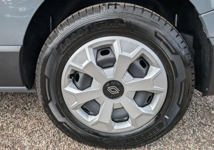 Gros plan sur la roue avant droite du Renault Trafic Fourgon gris, montrant le pneu et l'aile du véhicule.