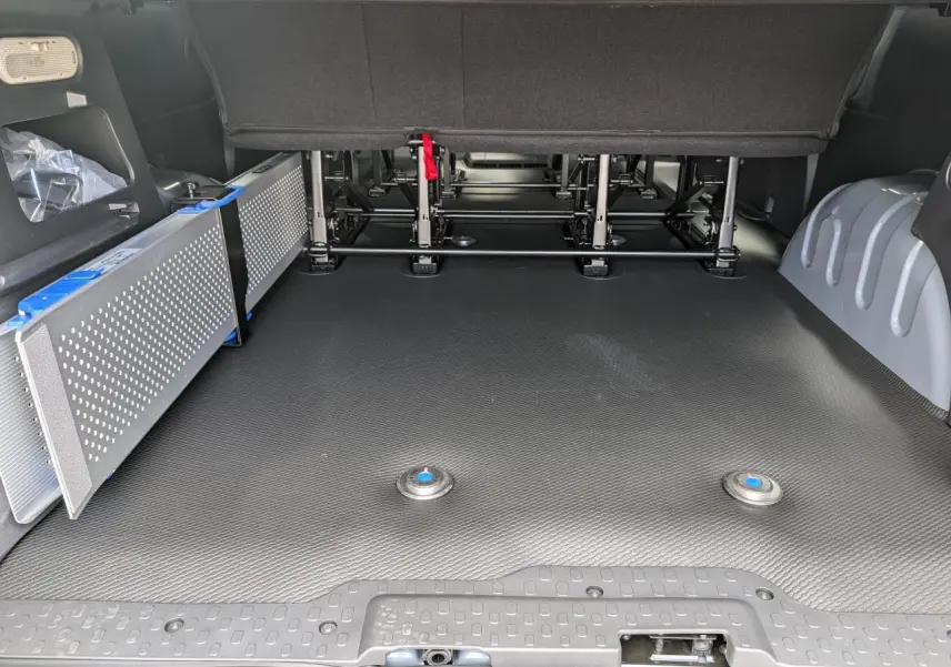 Vue intérieure arrière du Renault Trafic Fourgon gris, montrant le plancher avec rampes amovibles pour accès fauteuil roulant.