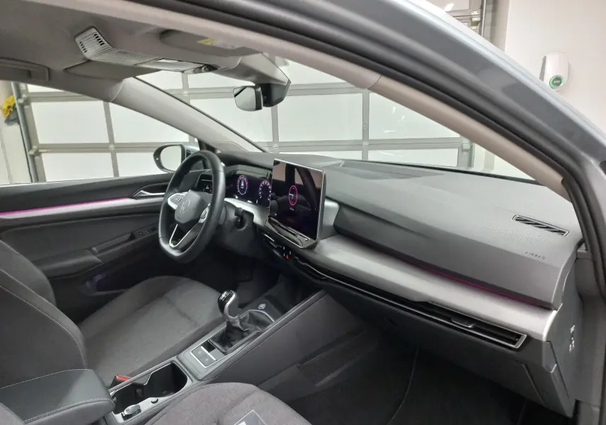 Vue intérieure côté conducteur de la Volkswagen Golf 1.5 eTSI 116 BVM6 avec tableau de bord moderne et éclairage d’ambiance violet.