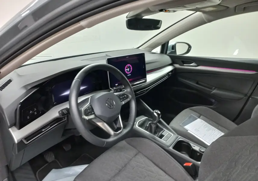 Vue intérieure côté conducteur de la Volkswagen Golf 1.5 eTSI 116 BVM6 avec tableau de bord moderne et éclairage d'ambiance violet.