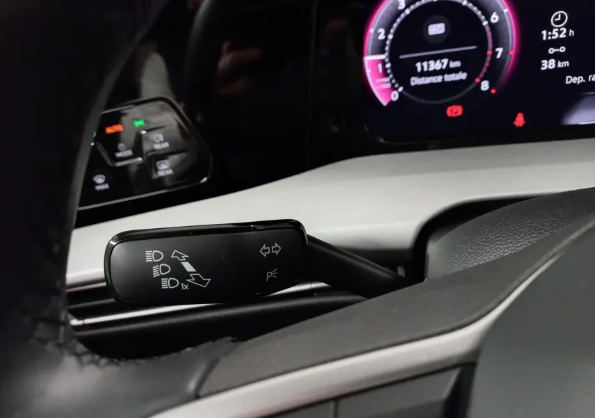 Gros plan sur la commande des clignotants à gauche du volant dans le tableau de bord numérique d'une Volkswagen Golf argent Dolomite.