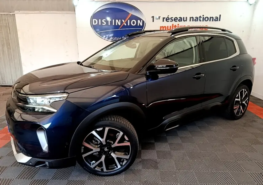 SUV Citroën C5 Aircross bleu foncé vu de trois quarts avant droit, avec jantes alliage et barres de toit noires.