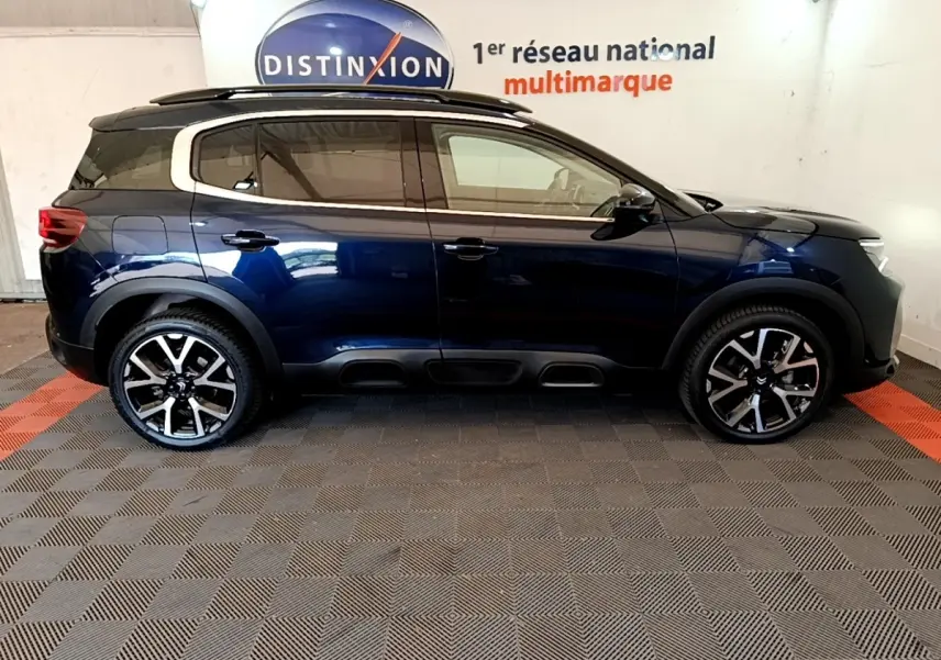 Vue de profil côté gauche d'un Citroën C5 Aircross 2023 bleu foncé avec jantes alliage et toit noir.