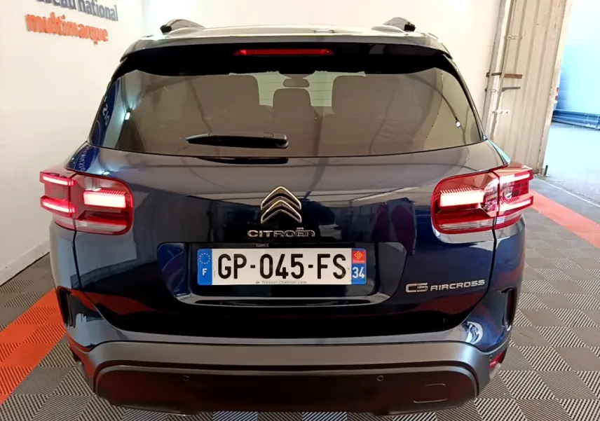 Vue arrière d'un Citroën C5 Aircross bleu foncé avec feux allumés, immatriculé en France, en intérieur.