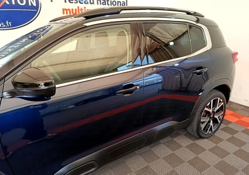 Vue côté droit du Citroën C5 Aircross 2023 bleu foncé avec jantes alliage et barres de toit noires.