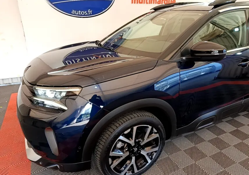 Vue 3/4 avant droit d'une Citroën C5 Aircross 2023 bleu foncé avec jantes alliage et phares LED distinctifs.