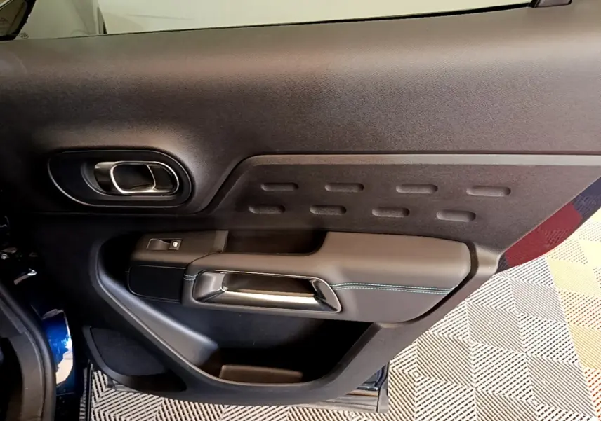 Gros plan sur la porte intérieure côté gauche du Citroën C5 Aircross 2023, finition noire avec surpiqûres bleues.