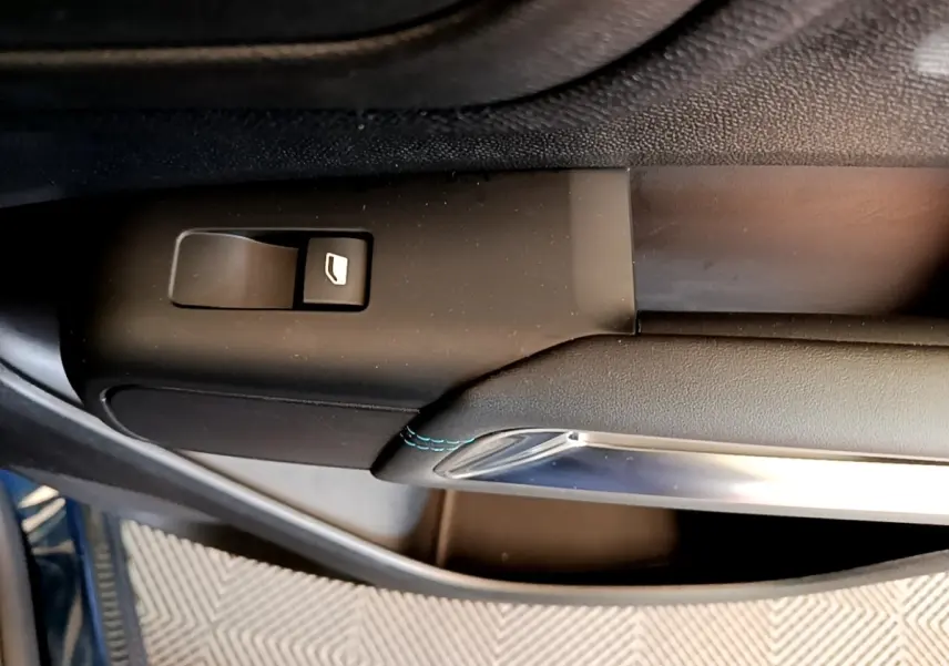 Gros plan sur la commande de lève-vitre côté conducteur du Citroën C5 Aircross 2023 avec surpiqûres bleues.