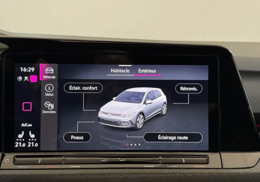 Écran tactile intérieur montrant une Volkswagen Golf vue 3/4 avant en gris clair avec options d'éclairage et pneus.