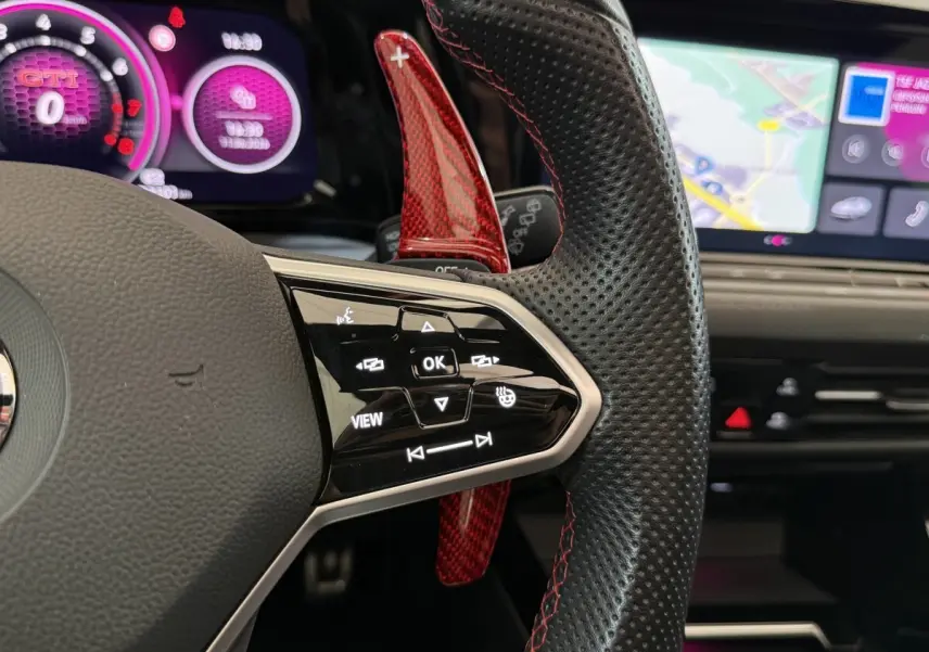 Gros plan sur le volant cuir perforé avec palettes rouges et affichage numérique violet de la Volkswagen Golf GTI Clubsport 2022.