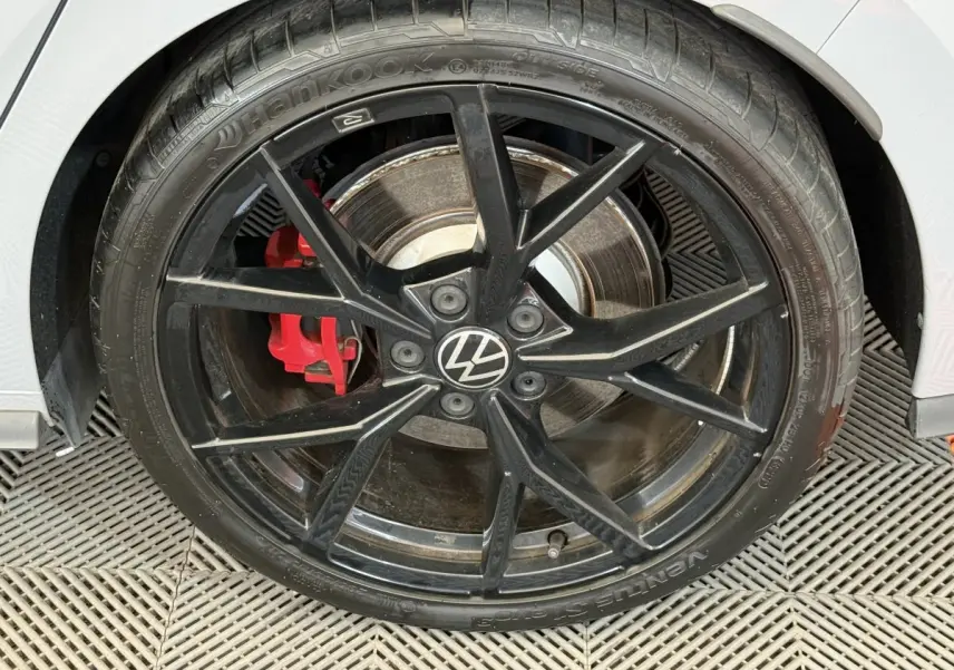 Gros plan sur la roue avant droite noire avec étrier de frein rouge d'une Volkswagen Golf GTI Clubsport gris foncé.