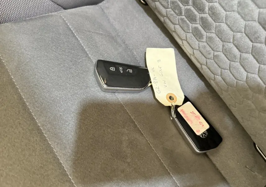 Clé de voiture Volkswagen Golf 2.0 TSI 300 DSG7 GTI Clubsport posée sur siège arrière gris foncé avec tissu texturé.
