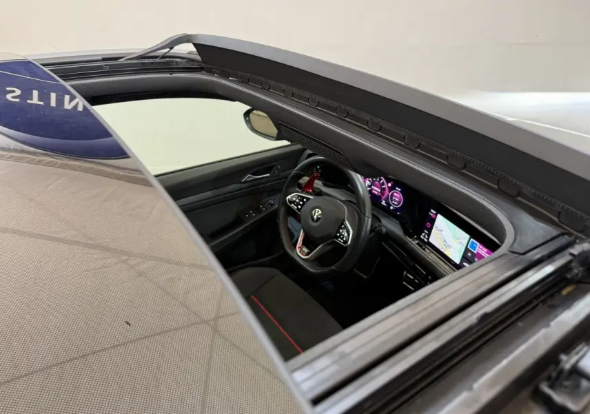 Vue intérieure côté conducteur de la Volkswagen Golf GTI Clubsport gris foncé, avec tableau de bord numérique et écran tactile.