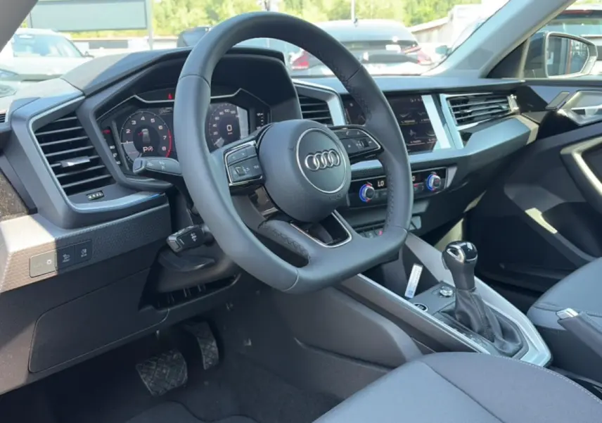 Vue intérieure côté conducteur de l'Audi A1 Sportback 2026 avec volant cuir multifonction et tableau de bord digital.