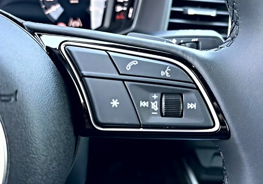 Gros plan sur les commandes multifonctions du volant cuir noir de l'Audi A1 Sportback 2026, avec touches d'appel et volume.