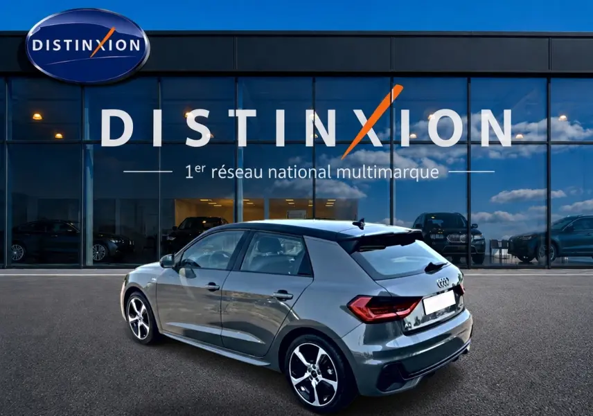 Audi A1 Sportback gris chronos vue 3/4 arrière droit avec jantes alu et toit noir devant showroom Distinxion.