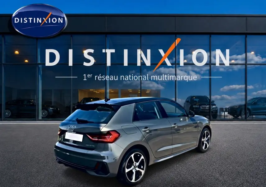 Audi A1 Sportback gris chronos vue 3/4 arrière droit avec jantes alu et becquet arrière, devant une vitrine Distinxion.