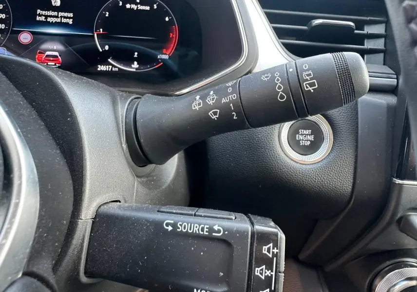 Gros plan intérieur sur la commande de phares et le bouton Start Engine Stop du Renault Captur rouge nacré 2024.