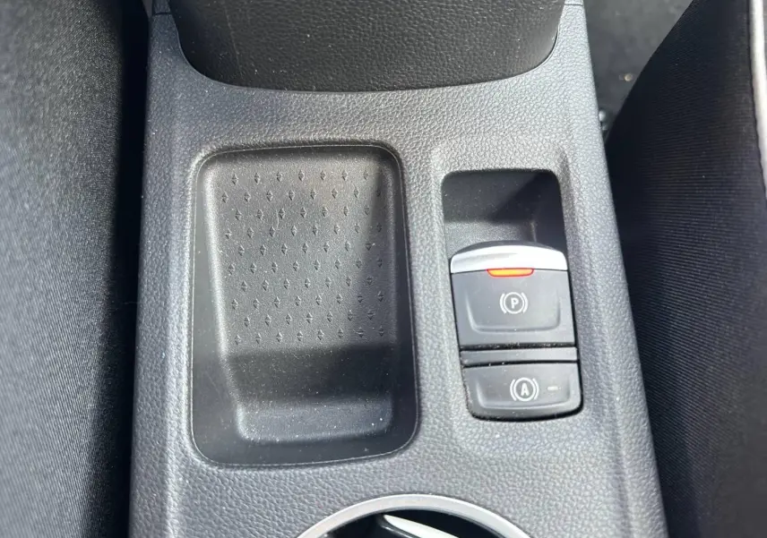 Détail de la console centrale du Renault Captur 2024 montrant les boutons du frein à main électrique et du démarrage auto, en plastique noir.