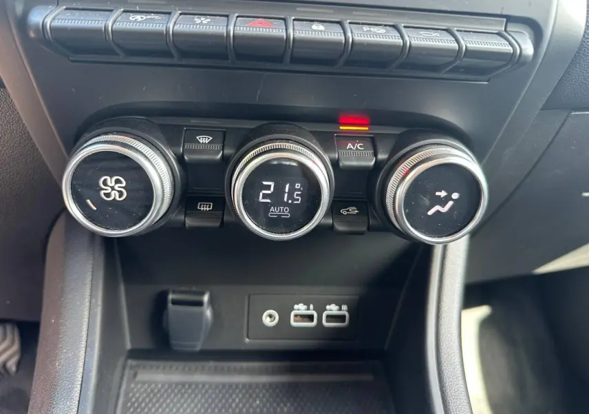 Gros plan sur les commandes de climatisation et les ports USB du Renault Captur 2024 rouge Flamme nacré.