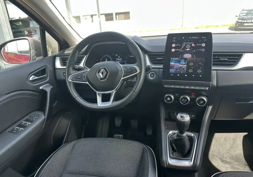 Vue intérieure avant de la Renault Captur 2024, montrant le volant multifonction, la boîte manuelle et l’écran tactile central.
