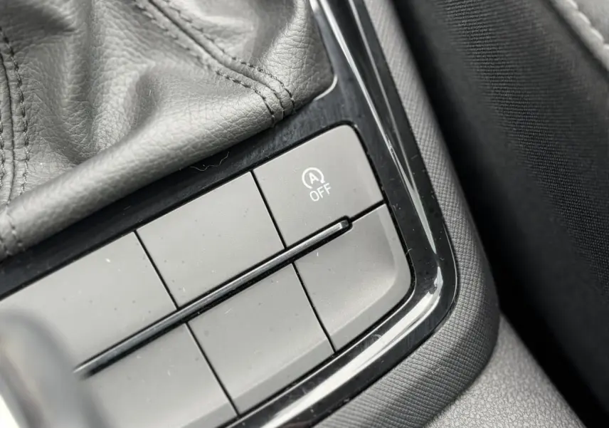 Gros plan sur le bouton de désactivation du système start-stop dans l'accoudoir central d'une Skoda Scala 2024.