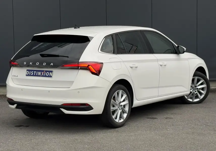 Vue 3/4 arrière droite d'une Skoda Scala blanche Candy avec jantes alliage 17 pouces et vitres teintées.