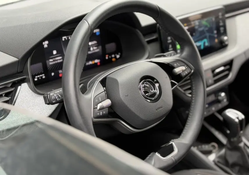 Gros plan sur le volant cuir multifonctions de la Skoda Scala 2024, avec tableau de bord digital en arrière-plan.