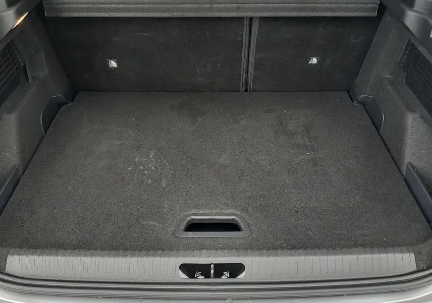 Coffre ouvert vu de l'arrière d'une Citroën C4 Hybrid 136 gris acier, montrant un espace de chargement propre et spacieux.