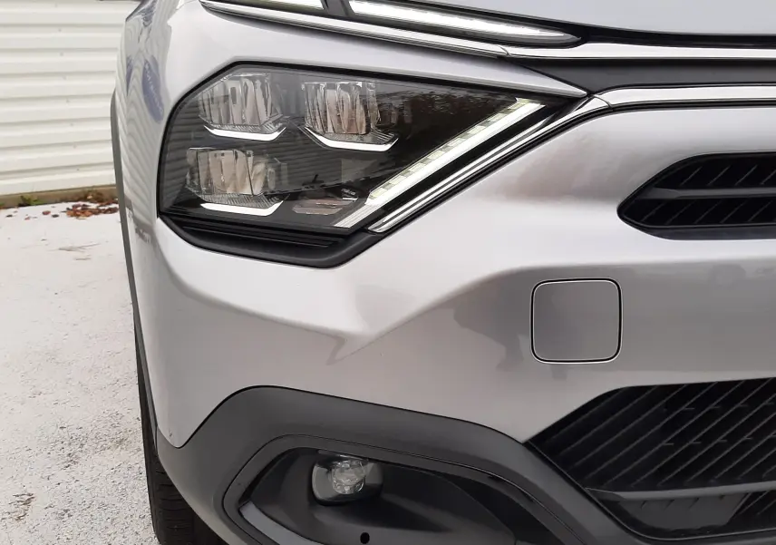 Gros plan sur l'avant gauche de la Citroën C4 gris acier 2024, mettant en valeur ses phares LED et la calandre noire.