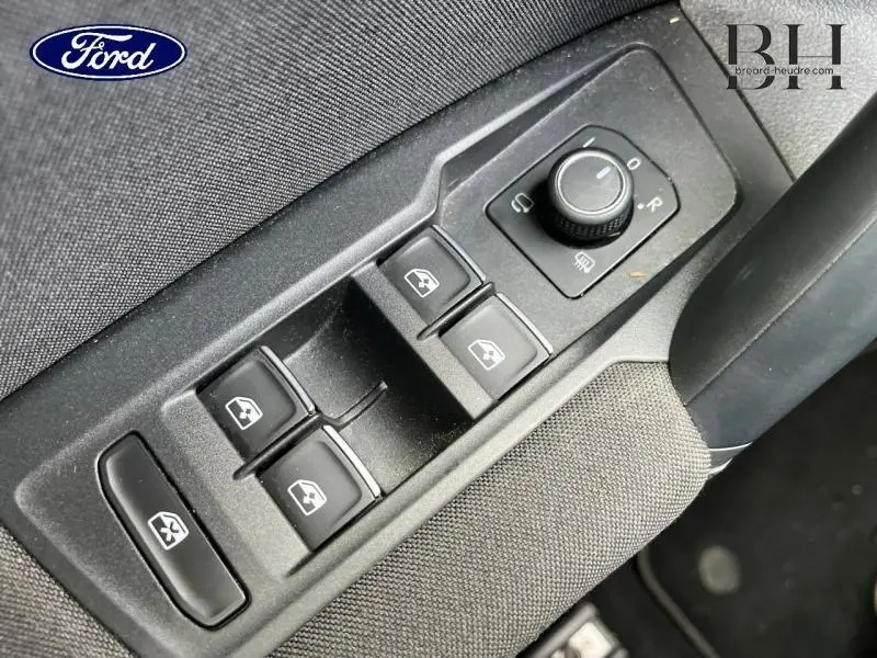 Vue rapprochée des commandes de lève-vitres et rétroviseurs sur la porte côté conducteur du Volkswagen Tiguan noir nacré.