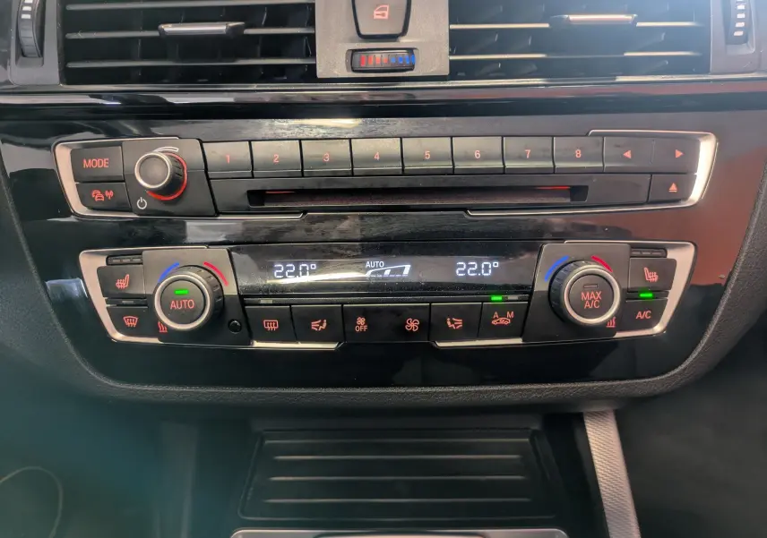 Gros plan sur la console centrale noire du BMW Série 2 Cabriolet 218dA, affichant la climatisation automatique à 22°C.