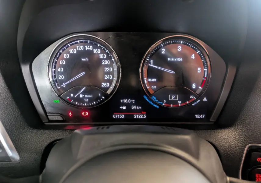 Vue rapprochée du tableau de bord numérique d'une BMW Série 2 Cabriolet noire, affichant vitesse, compte-tours et informations de conduite.