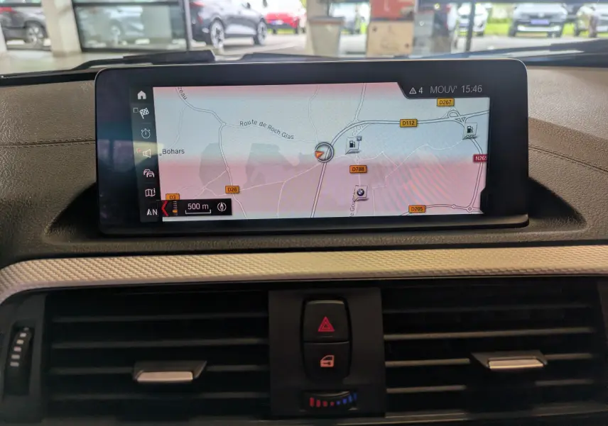 Vue intérieure centrée sur l'écran de navigation du tableau de bord d'une BMW Série 2 Cabriolet 218d noire.