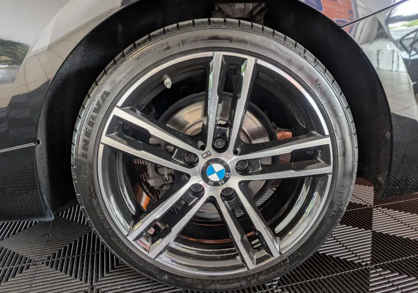 Gros plan sur la jante avant droite noire et argentée d’un BMW Série 2 Cabriolet 218dA 2020 avec logo BMW au centre.