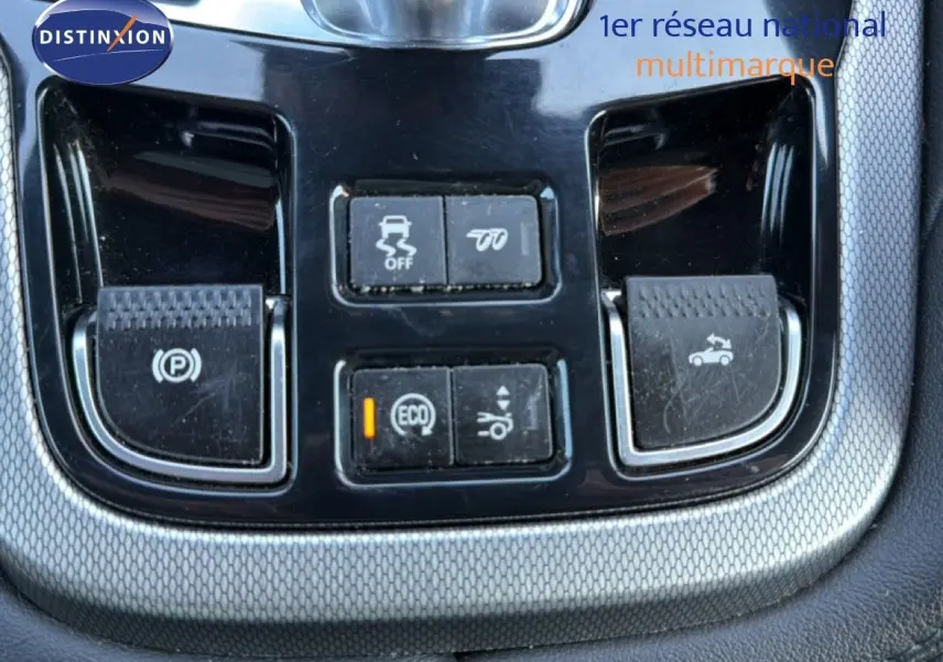 Gros plan sur les commandes centrales noires et argentées du tableau de bord d'une Jaguar F-TYPE gris 2013.