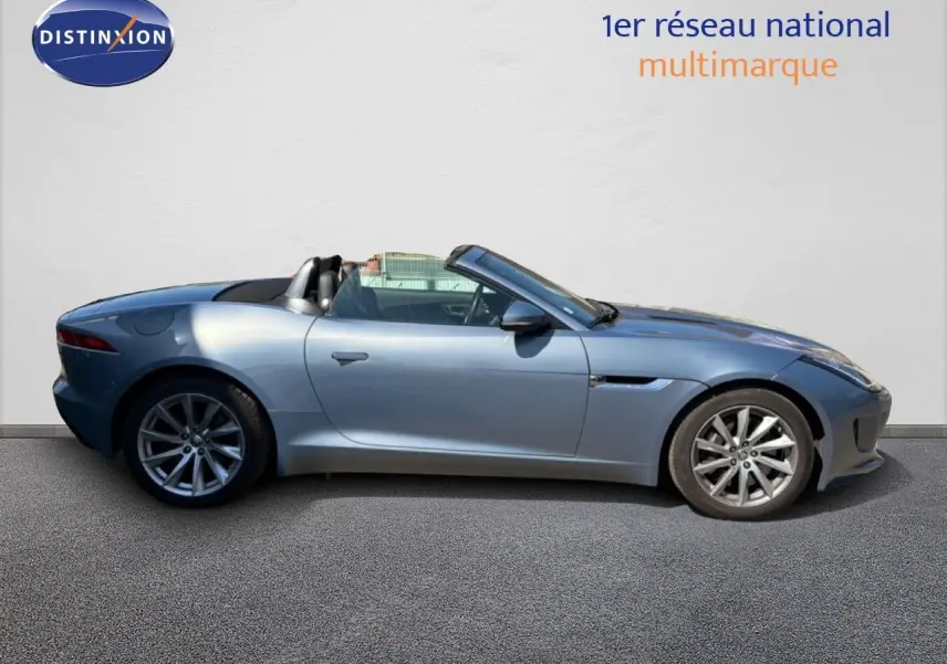 Jaguar F-TYPE cabriolet gris vue de profil côté gauche, toit ouvert et jantes alliage visibles.