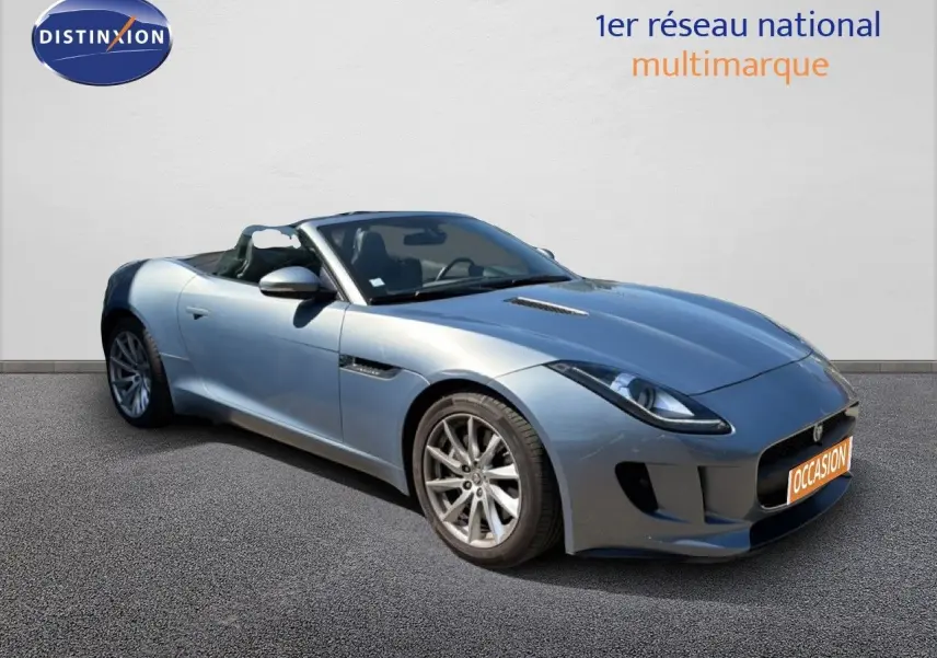 Jaguar F-TYPE cabriolet gris vue 3/4 avant droit, toit ouvert, jantes alliage et lignes sportives marquées.