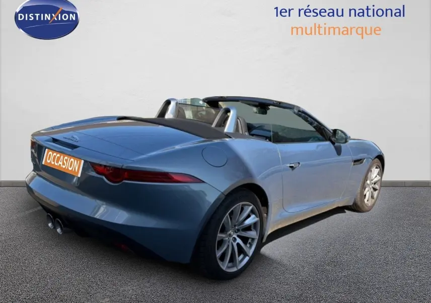 Jaguar F-TYPE cabriolet gris vue 3/4 arrière droit, jantes alliage et double sortie d’échappement visible.